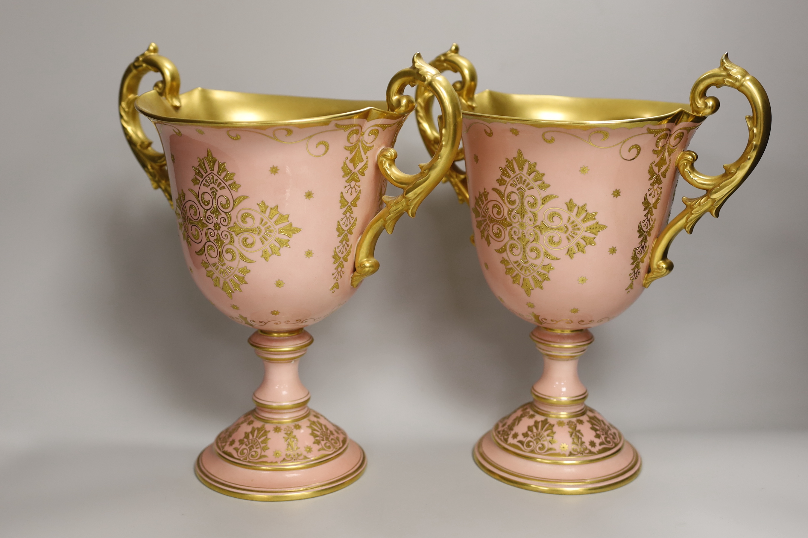 A pair of large Coalport salmon pink ground two handled loving cups, 28.5cm